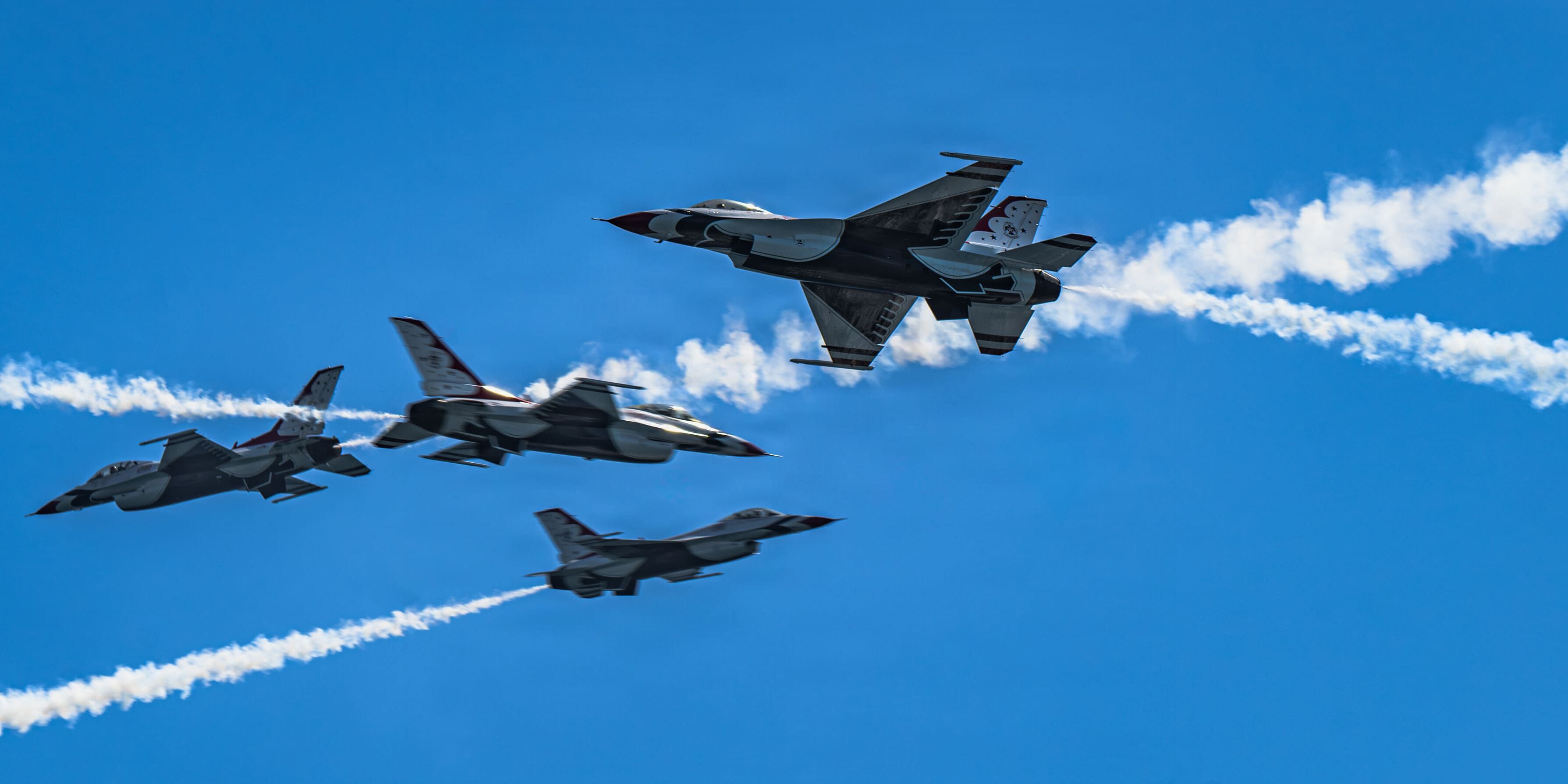 Five U.S. Air Force Thunderbirds performing an aerial maneuver with smoke trails